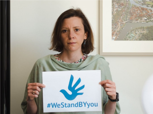 Anikó Merten holding a WeStandBYyou sign